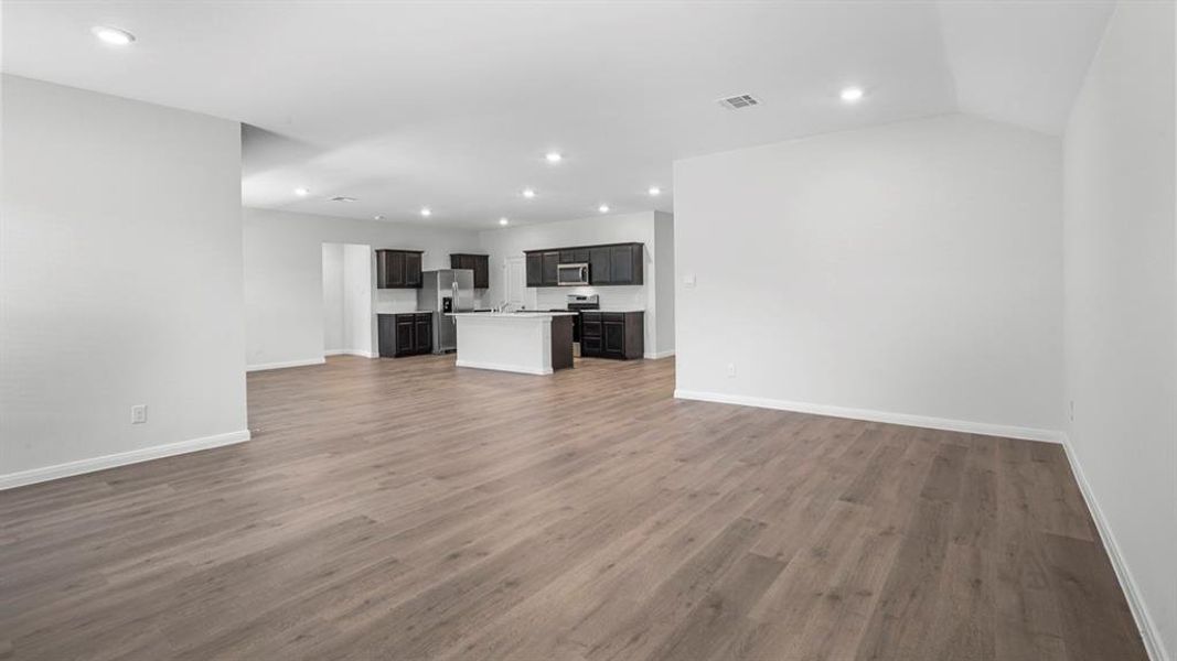 Unfurnished living room featuring dark wood-type flooring and recessed lighting