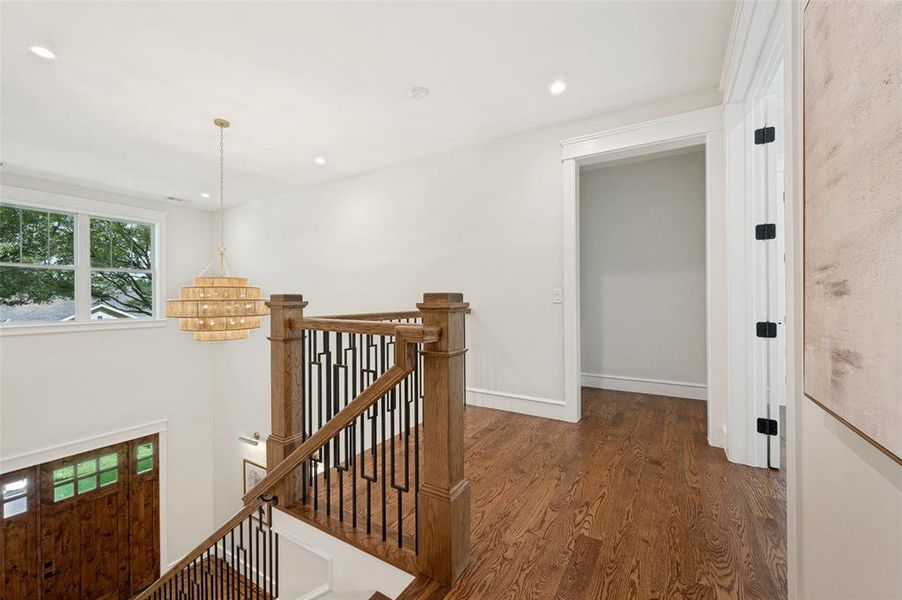 Hardwood flooring throughout the upper landing, featuring a contemporary chandelier and recessed lighting