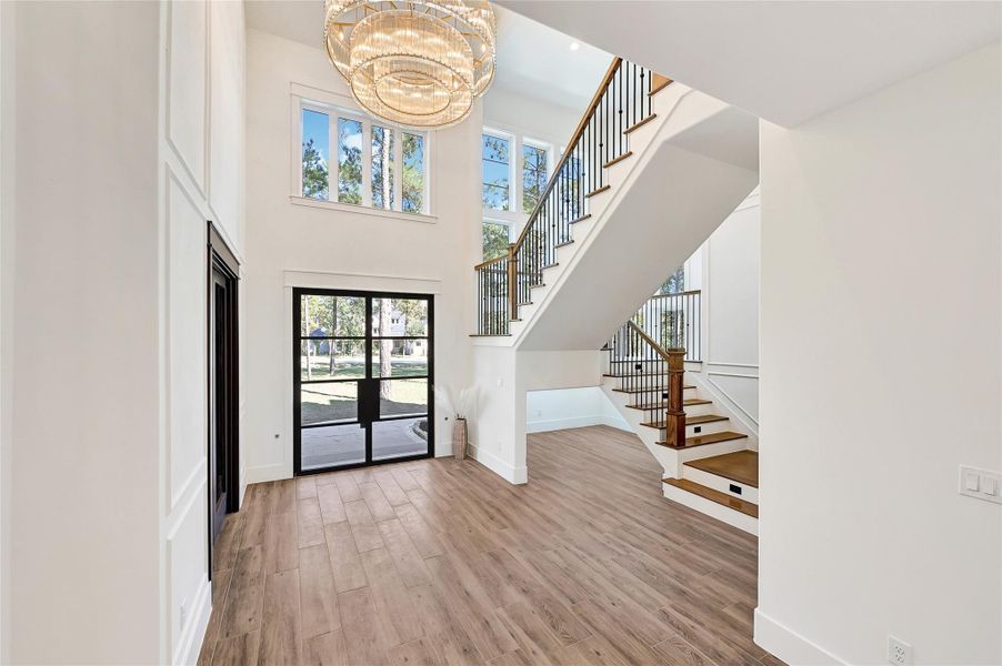 Grand foyer, featuring a elegant chandelier and striking floating staircase, capturing the elegance and architectural detail of the space.