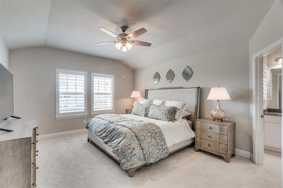 Carpeted bedroom with ensuite bathroom, ceiling fan, and lofted ceiling