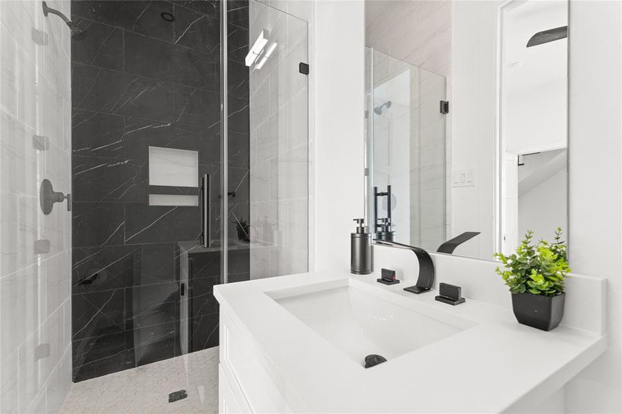 Bathroom featuring a marble finish shower and vanity