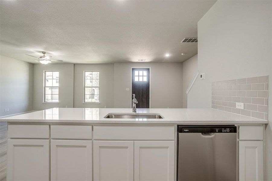 Kitchen featuring stainless steel dishwasher, white cabinetry, ceiling fan, and light countertops Kitchen featuring stainless steel dishwasher, white cabinetry, ceiling fan, and light countertops