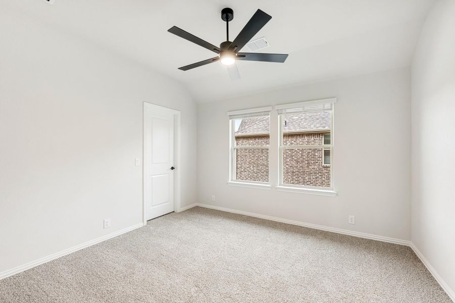 Empty bedroom with carpet flooring, black ceiling fan, and double window with natural light