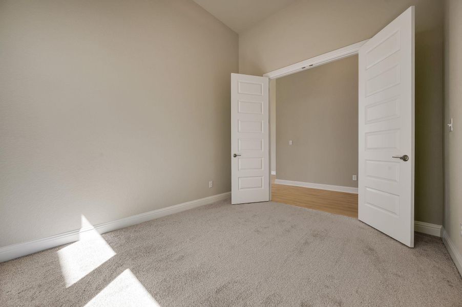 Unfurnished bedroom with light carpet and baseboards