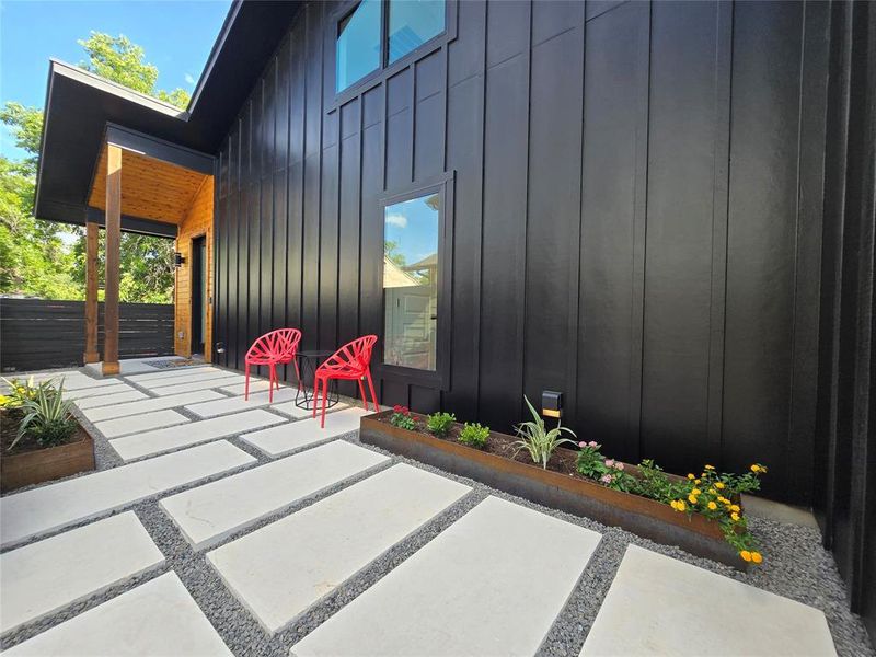 Custom large paver stone landscaping leading up to front door with metal planter boxes that provide just enough greenery. Drip irrigation in the planter boxes.