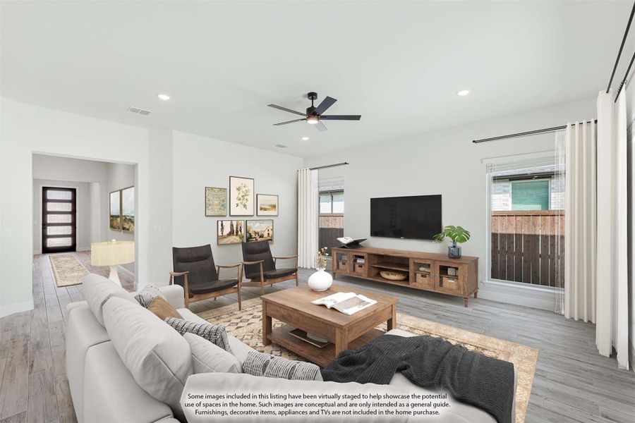 Open living room with gray sofa, wood coffee table, ceiling fan, and hardwood floors leading to front entry