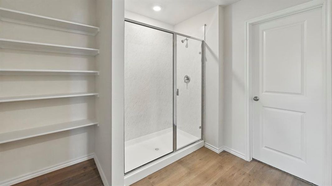 Bathroom featuring light wood-type flooring, a shower stall, recessed lighting, and a closet