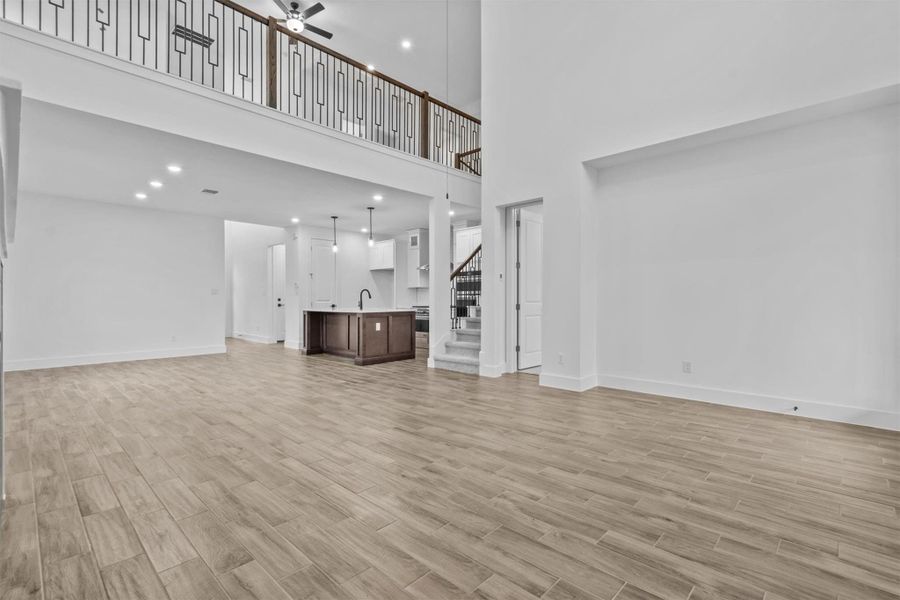 Unfurnished living room with ceiling fan, a high ceiling, and sink