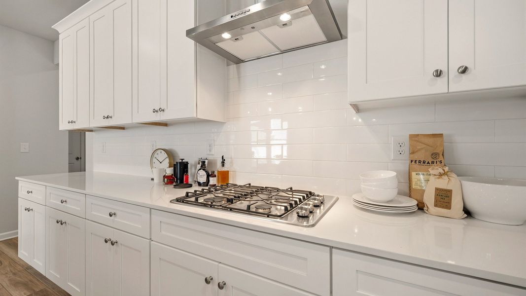Kitchen with tile backsplash, quartz countertops, and white cabinetry Kitchen with tile backsplash, quartz countertops, and white cabinetry