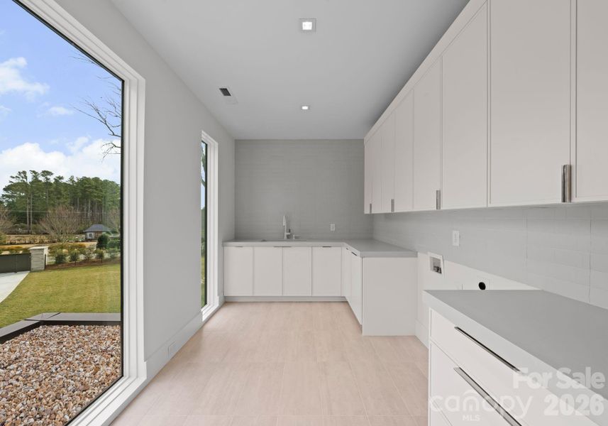Laundry room with extensive counter space and cabinetry. Laundry room with extensive counter space and cabinetry.