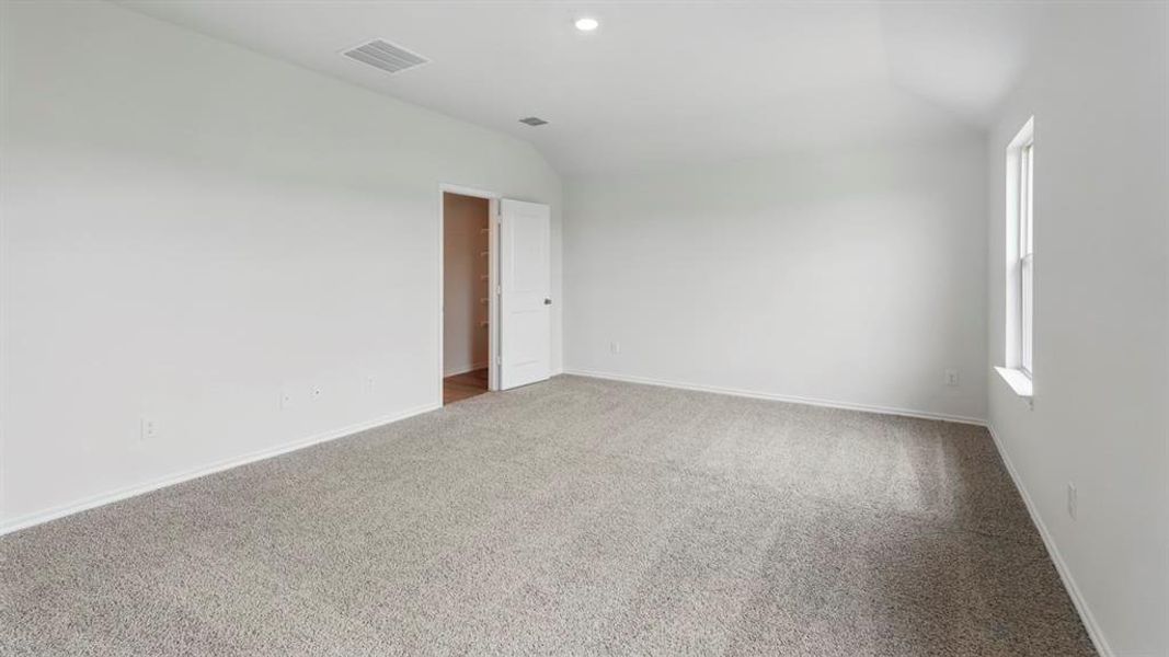 Spacious room featuring neutral carpeting, white walls, a single window, recessed lighting, and a closet with a solid white door