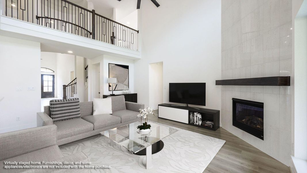 Living area featuring a tiled fireplace, wood finished floors, stairs, and a high ceiling