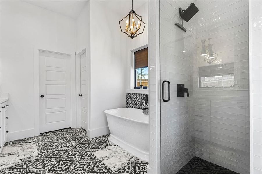 Full bathroom with a stall shower, baseboards, a notable chandelier, a freestanding tub, and vanity Full bathroom with a stall shower, baseboards, a notable chandelier, a freestanding tub, and vanity