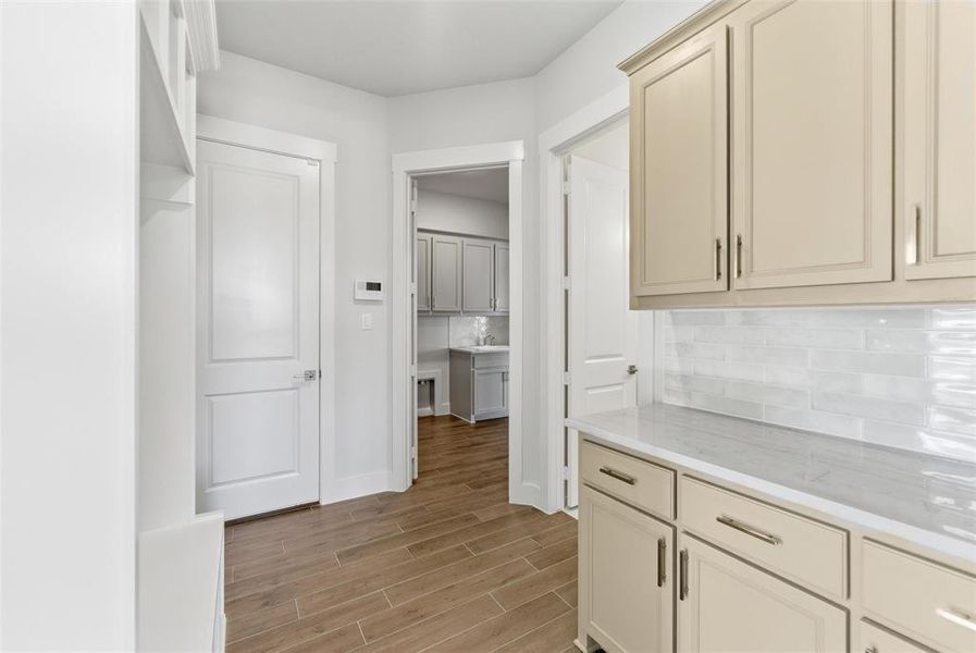 Kitchen with wood tiled floors, backsplash, and cream cabinets