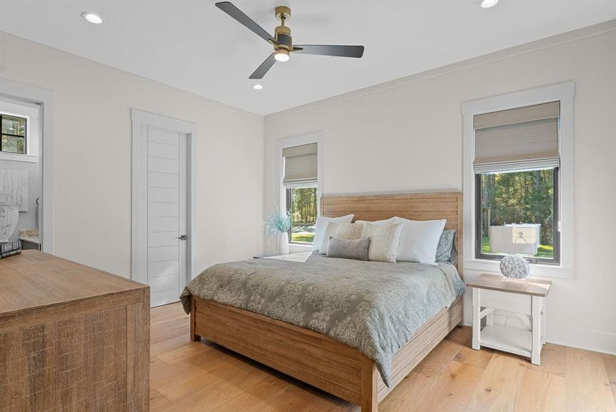 Bedroom with multiple windows, light wood-style floors, a ceiling fan, and recessed lighting