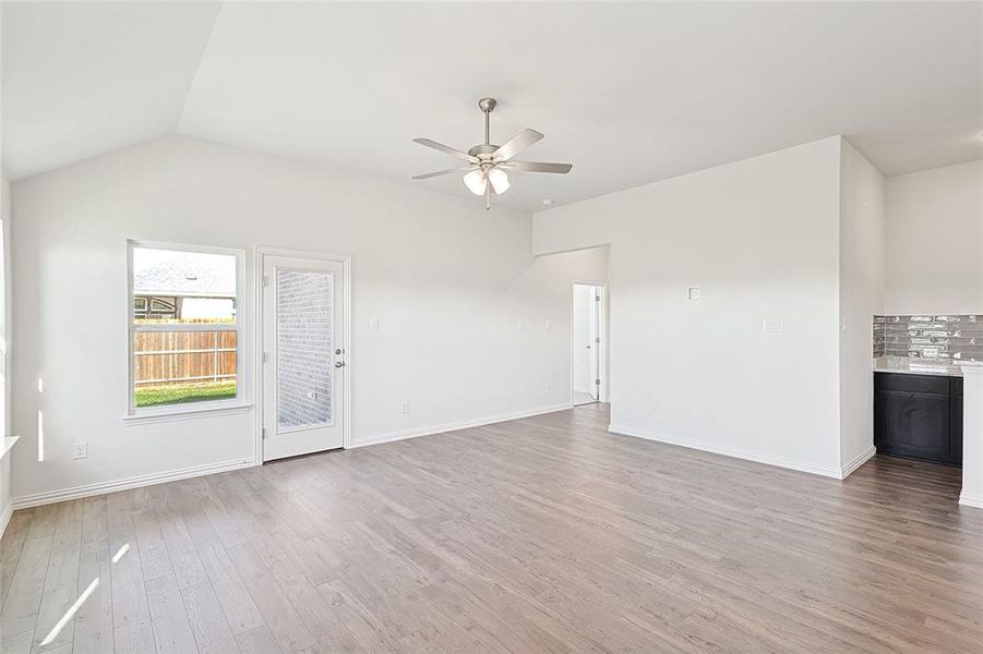 Unfurnished living room featuring ceiling fan, vaulted ceiling, and light wood-type flooring