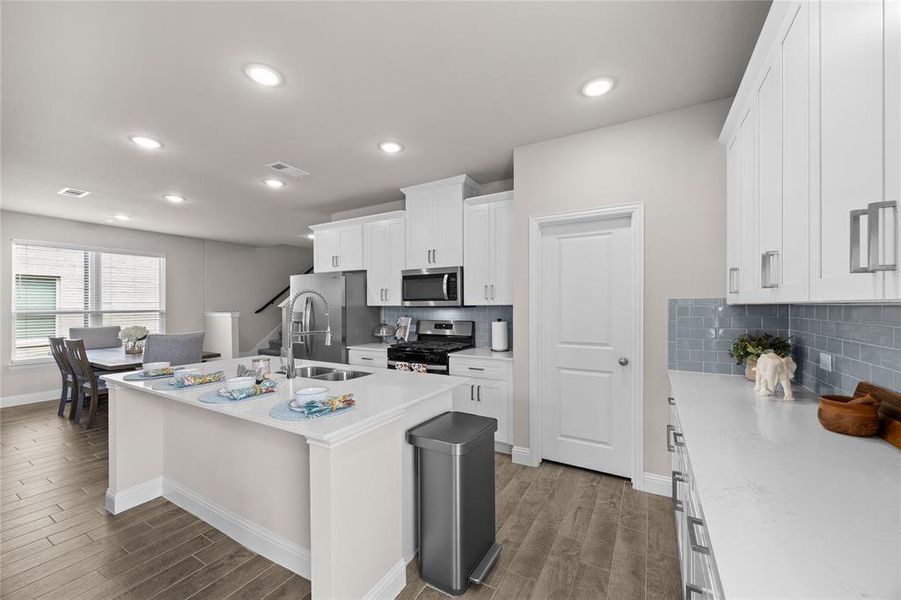 At the center of it all sits a large island with an undermount double sink, breakfast bar seating, and plenty of prep space. Recessed LED lighting and bright windows ensure the space is exceptionally well-lit, and you will absolutely love the oversized walk-in pantry that offers incredible storage for all your kitchen essentials.