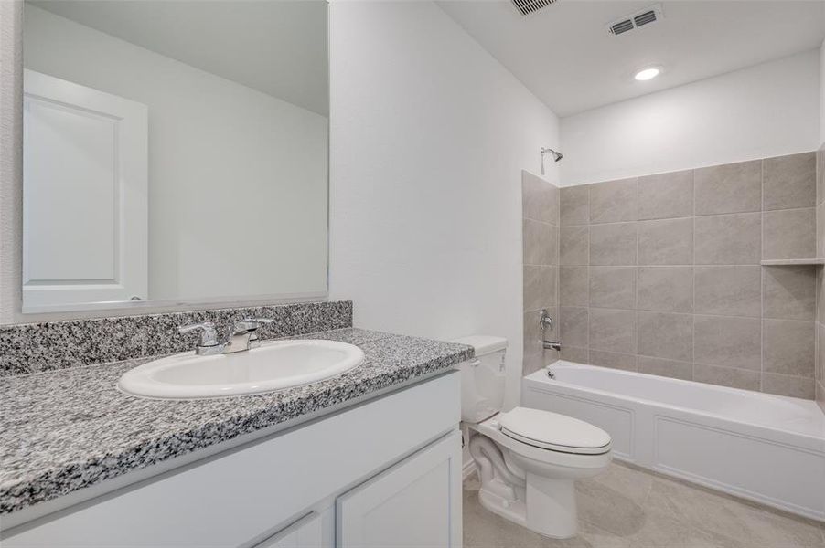 Full bathroom with tile floors, tiled shower / bath combo, large vanity, and toilet Full bathroom with tile floors, tiled shower / bath combo, large vanity, and toilet