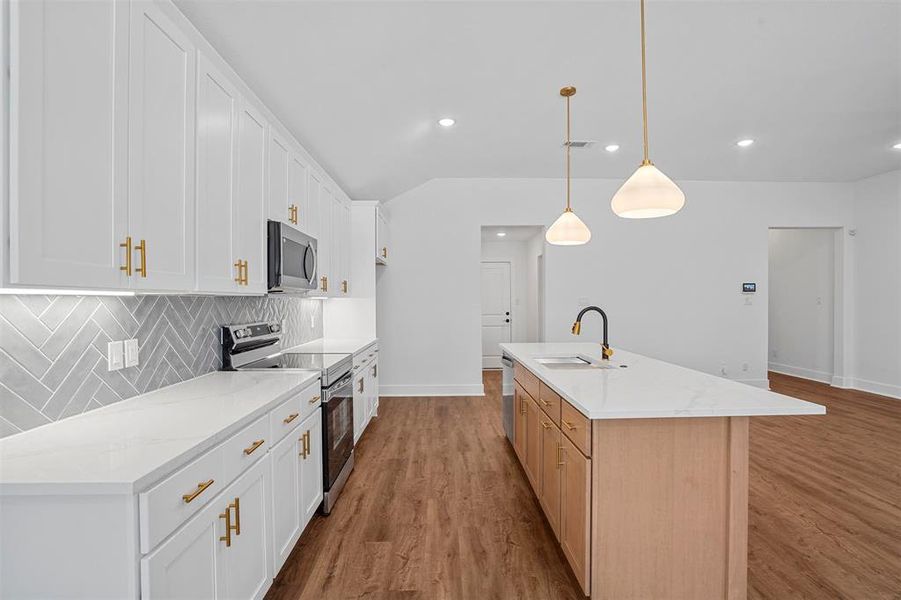 Kitchen with a sink, tasteful backsplash, appliances with stainless steel finishes, and wood finished floors