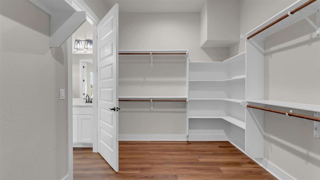 Custom built-in shelving and hanging rods maximize storage in this walk-in closet with wood floors. Custom built-in shelving and hanging rods maximize storage in this walk-in closet with wood floors.