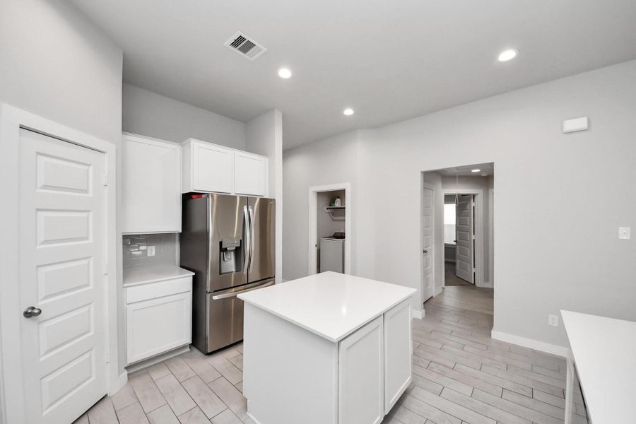 Kitchen layout offers convenient access to the laundry room located just across from it, while the hallway straight ahead leads to the two secondary bedrooms, a full bathroom, and a linen closet.