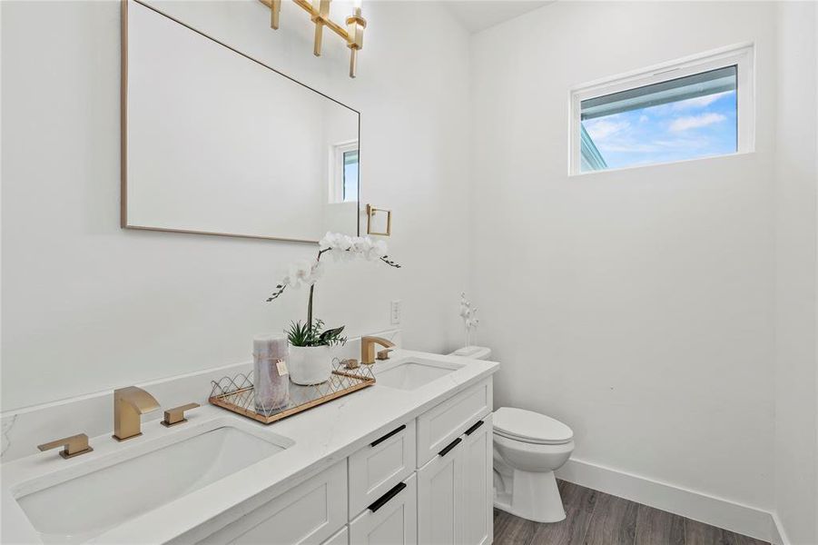 Bathroom with double vanity, wood finished floors, and plenty of natural light
