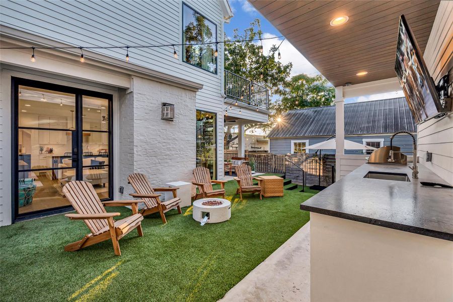 View of green lawn featuring an outdoor fire pit, a patio area, area for grilling, and a balcony View of green lawn featuring an outdoor fire pit, a patio area, area for grilling, and a balcony