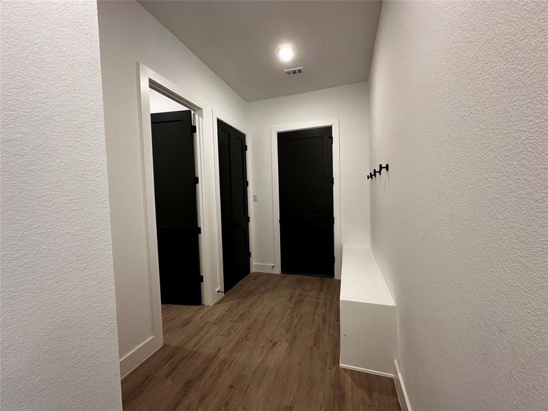 Hallway from garage with half bath, mechanical closet, and mudbench