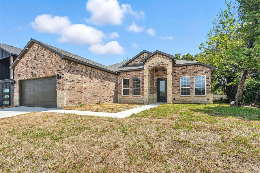 French provincial home featuring brick siding, a front lawn, an attached garage, and concrete driveway French provincial home featuring brick siding, a front lawn, an attached garage, and concrete driveway