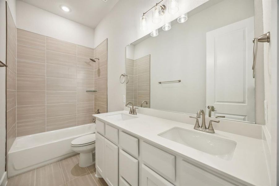 Full bathroom with vanity, tile patterned floors, tiled shower / bath combo, and toilet