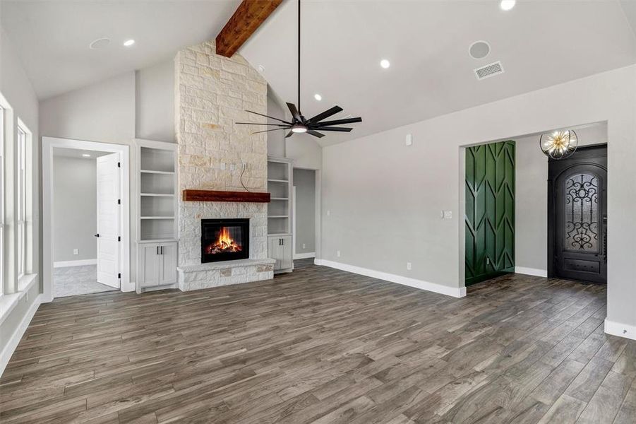 Unfurnished living room featuring built in features, a fireplace, lofted ceiling with beams, hardwood / wood-style flooring, and ceiling fan