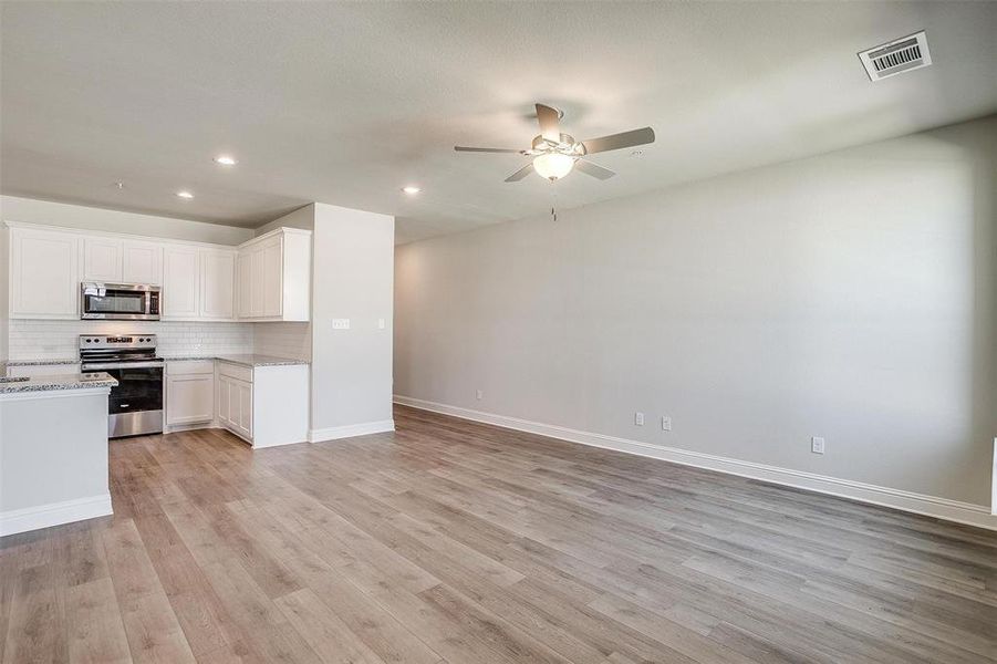 Kitchen featuring stainless steel appliances, white cabinetry, decorative backsplash, ceiling fan, and recessed lighting