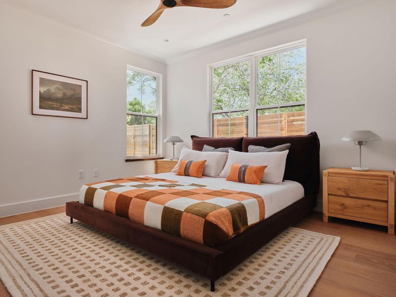 Bedroom with light wood-style flooring, crown molding, and ceiling fan