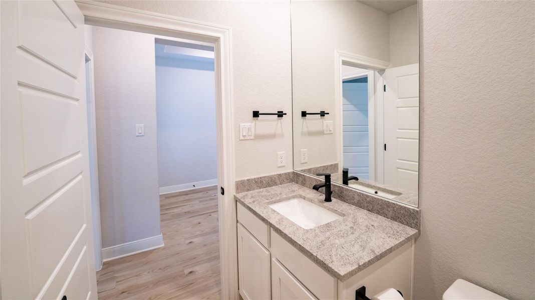 Half bathroom featuring vanity, a textured wall, and light wood-type flooring Half bathroom featuring vanity, a textured wall, and light wood-type flooring