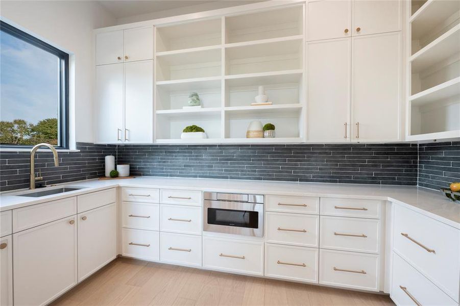 Kitchen with white cabinetry, light hardwood / wood-style flooring, tasteful backsplash, and sink