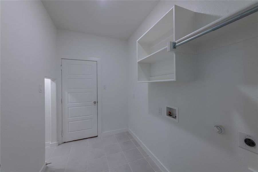 Washroom featuring electric dryer hookup, hookup for a washing machine, gas dryer hookup, light tile patterned floors, and baseboards
