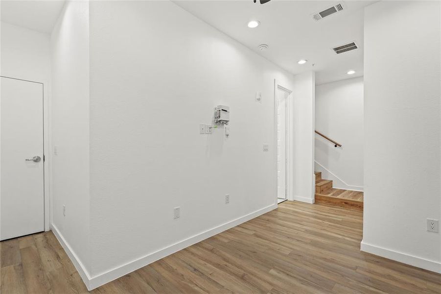 Hallway with light wood-style flooring, recessed lighting, and stairs