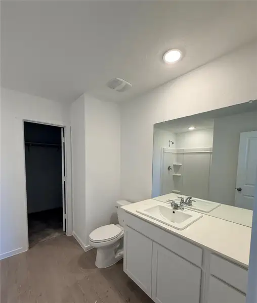 Full bathroom featuring a walk in closet, vanity, light wood-type flooring, a shower stall, and a textured ceiling Full bathroom featuring a walk in closet, vanity, light wood-type flooring, a shower stall, and a textured ceiling