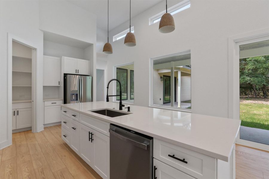 A well-lit kitchen with soaring ceilings, a central island, and modern amenities offers both function and style.