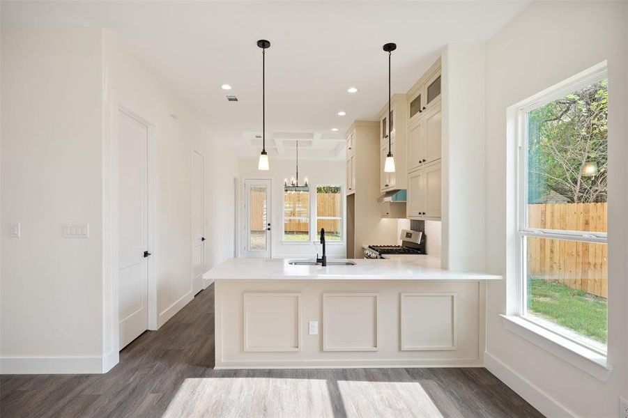 Kitchen featuring glass insert cabinets, a chandelier, light stone countertops, stainless steel gas range oven, and recessed lighting Kitchen featuring glass insert cabinets, a chandelier, light stone countertops, stainless steel gas range oven, and recessed lighting