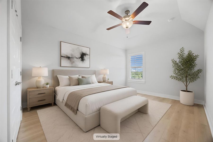 Naturally illuminated, this well-appointed bedroom features soaring vaulted ceilings and rich hardwood flooring.