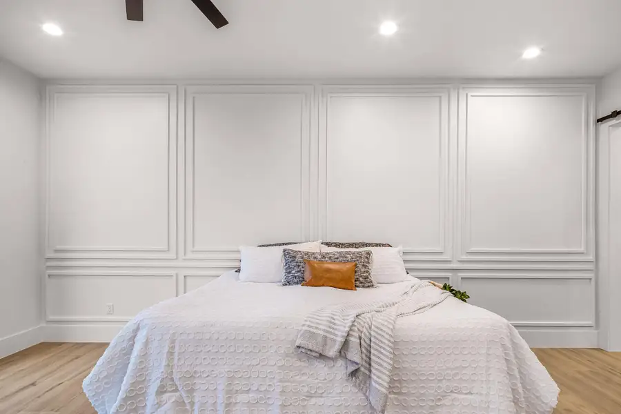 Bedroom featuring light wood-style floors, recessed lighting, a decorative wall, and ceiling fan