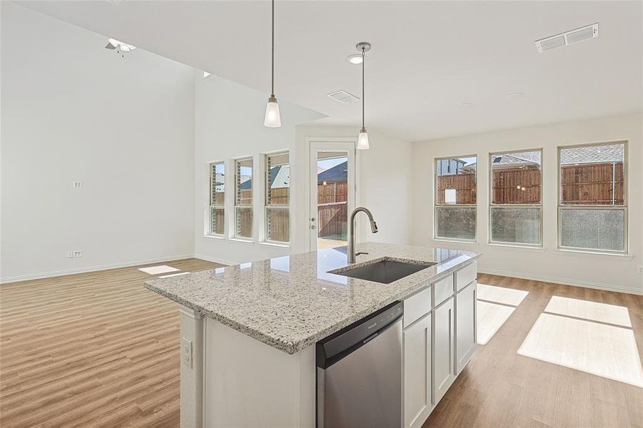 Kitchen featuring dishwasher, light stone countertops, light wood-style floors, and white cabinets