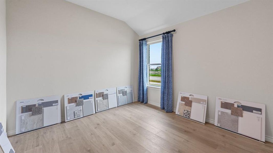 Unfurnished room featuring light wood finished floors and lofted ceiling Unfurnished room featuring light wood finished floors and lofted ceiling