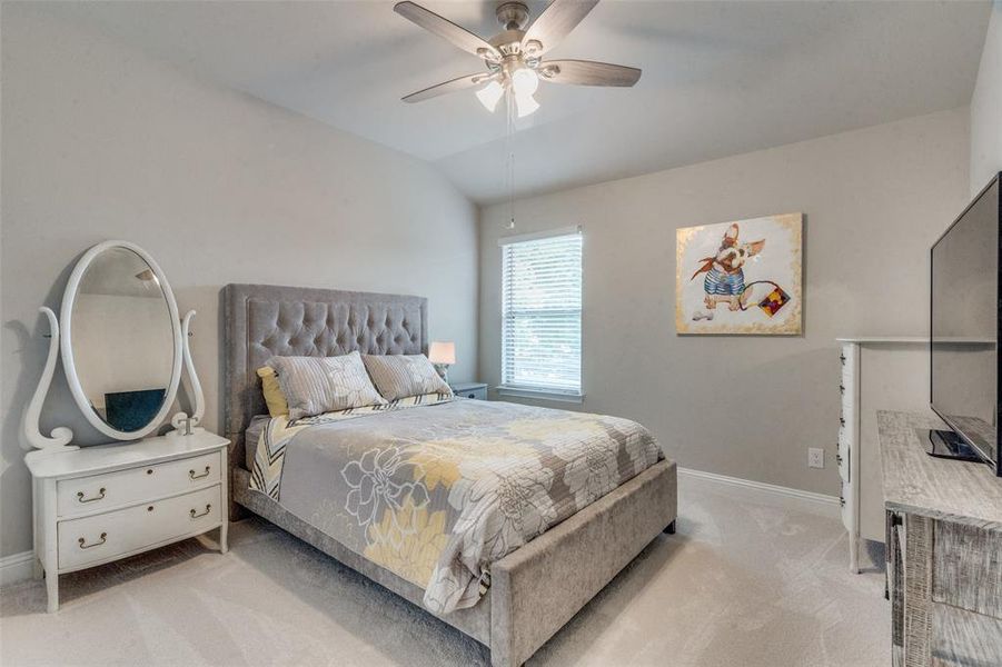 Bedroom with carpet, ceiling fan, and vaulted ceiling