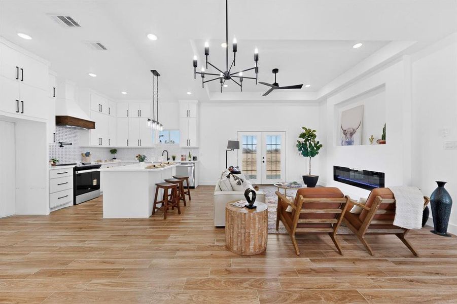 Living area with a chandelier, french doors, a glass covered fireplace, wood finish floors, and recessed lighting