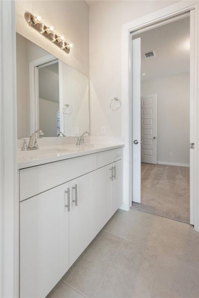 Full bath featuring double vanity, light tile patterned floors, and light colored carpet