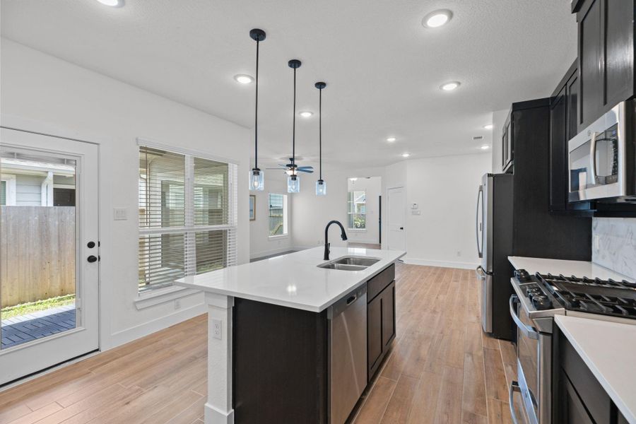 Opposite view of the spacious island kitchen featuring a large center island, breakfast bar with views to the backyard and dining/living areas.