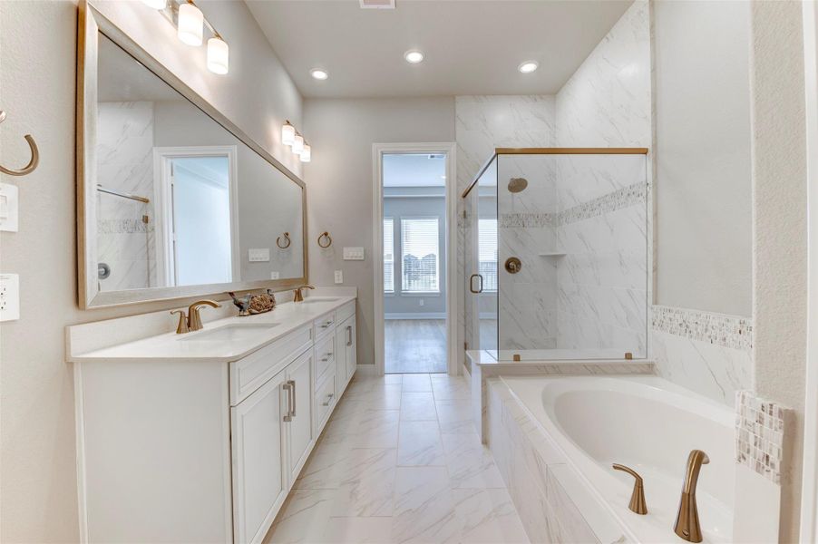 Primary bathroom with dual vanities, soaking tub, and glass-enclosed walk-in shower with modern finishes.