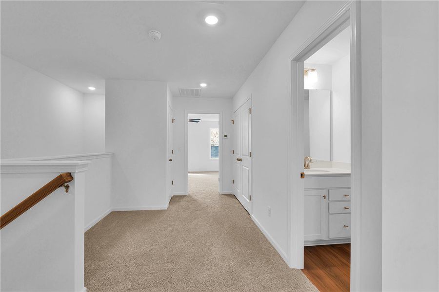 This spacious hallway features neutral carpet, bri